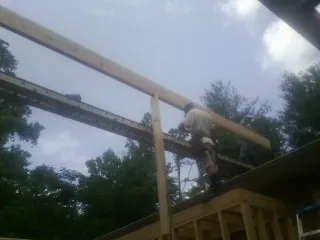 Carpenter setting a ridge beam over a new addition frame — Ice Dam Removal by Roofing Brothers in Aynor