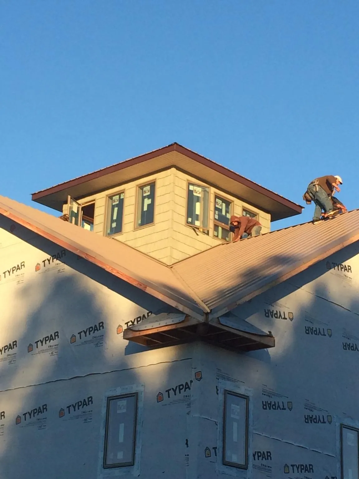 Roofers working around a rooftop cupola on a new metal roof at sunset — Roof Waterproofing in Aynor by Roofing Brothers